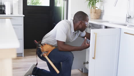 African-American-plumber-is-fixing-a-kitchen-sink