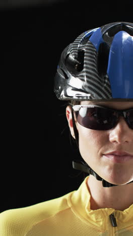 Vertical-video:-Caucasian-female-athlete-wearing-cycling-helmet,-black-background