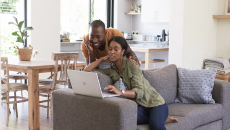 A-young-African-American-couple-uses-laptop-on-couch-at-home