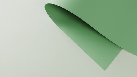 Close-up-of-green-rolled-piece-of-paper-on-white-background-with-copy-space-in-slow-motion