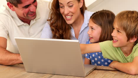 Smiling-family-using-laptop-together-at-table