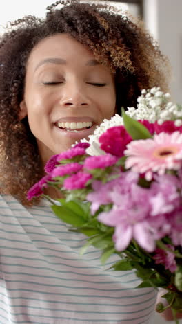 Vertical-video-of-happy-biracial-woman-with-flowers-having-valentine''s-day-video-call,-slow-motion