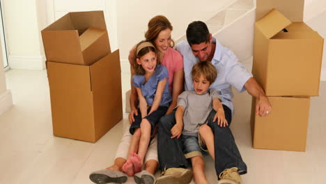 Happy-family-sitting-on-floor-in-their-new-home