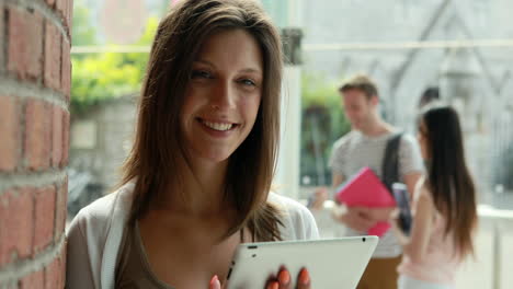 Student-using-tablet-and-friends-speaking-behind-her