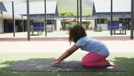 Biracial-girl-practicing-yoga-at-school