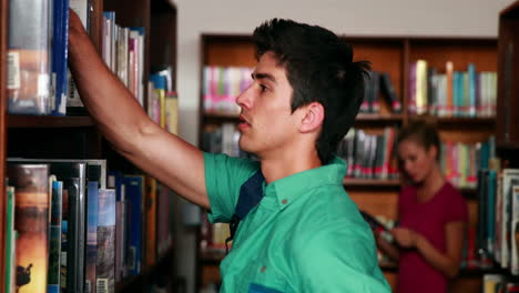 Estudiante-Guapo-Escogiendo-Un-Libro-En-La-Biblioteca