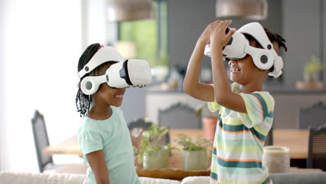 Two-African-American-siblings,-wearing-virtual-reality-headsets-at-home