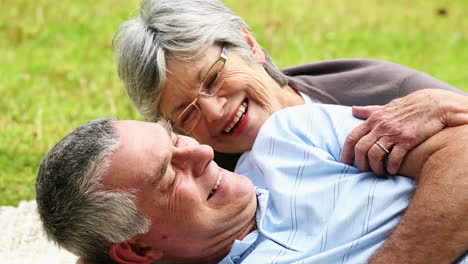 Affectionate-senior-couple-relaxing-in-the-park-lying-on-blanket