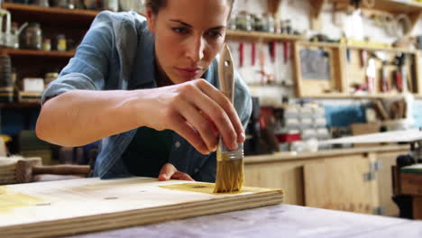 Centrarse-En-El-Carpintero-Pintando-Una-Tabla-De-Madera