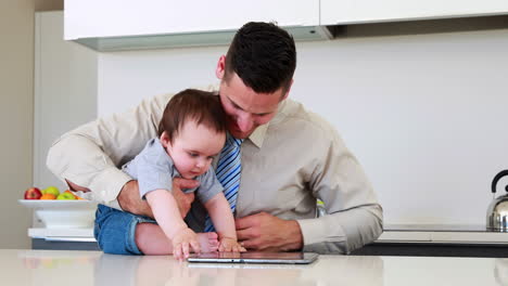 Father-holding-his-baby-before-work-and-using-tablet-pc