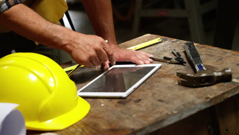 Focus-on-carpenter-hands-using-tablet