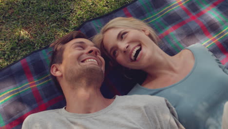 Couple-lying-down-on-picnic-blanket-in-the-park-on-sunny-day