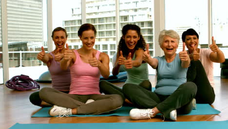 Group-of-women-in-fitness-studio-showing-thumbs-up