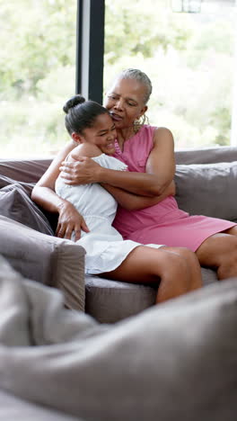 Vertical-video:-Biracial-young-granddaughter-hugging-African-American-senior-grandmother