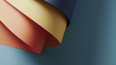Close-up-of-colourful-rolled-pieces-of-paper-on-blue-background-with-copy-space