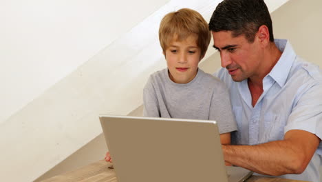Kleiner-Junge-Benutzt-Laptop-Mit-Seinem-Vater-Am-Tisch