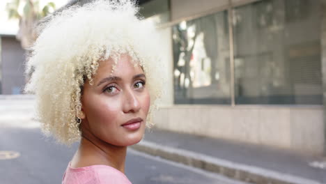 Young-biracial-woman-with-curly-blonde-hair-gazes-thoughtfully-with-copy-space-in-the-city