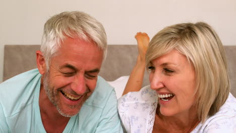 Couple-laughing-together-on-bed