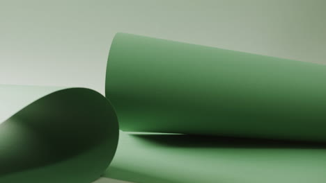 Close-up-of-green-rolled-pieces-of-paper-on-white-background-with-copy-space-in-slow-motion