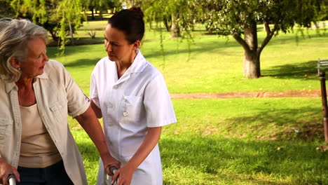 Nurse-talking-to-woman-using-walker-outside