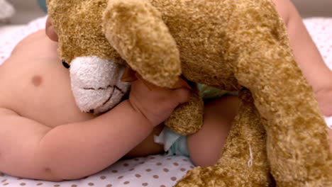 Baby-lying-in-crib-sucking-soother-holding-teddy