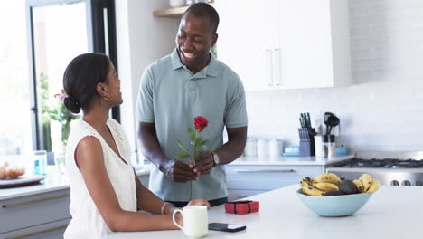 African-American-couple-shares-a-joyful-moment-in-the-kitchen,-exchanging-gifts