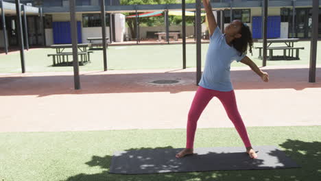 Biracial-girl-practicing-yoga-outdoors-on-a-mat-with-copy-space-in-school
