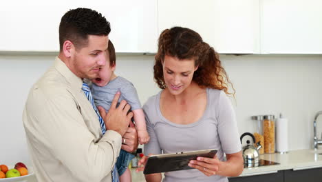 Parents-using-tablet-pc-while-father-holds-baby