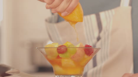 Mujer-Exprimiendo-Naranja-Sobre-Su-Ensalada-De-Frutas