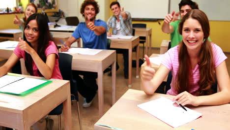 Schüler-Lächeln-Und-Strecken-Im-Klassenzimmer-Den-Daumen-In-Die-Kamera
