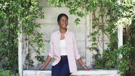 A-young-African-American-woman-smiles-in-a-leafy-alcove