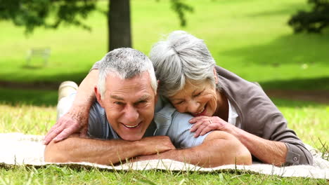 Senior-couple-relaxing-in-the-park-lying-on-a-blanket