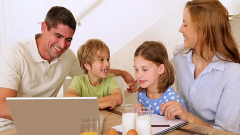 Happy-family-using-laptop-together-at-the-breakfast-table