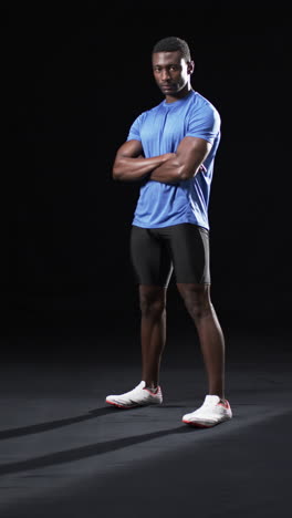 Vertical-video:-African-American-male-athlete-posing-confidently,-black-background