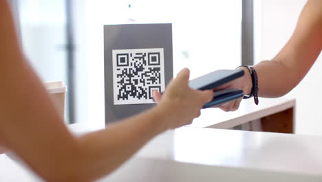 A-biracial-young-woman-holding-smartphone,-scanning-QR-code