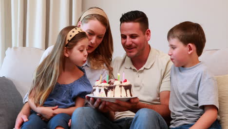 Happy-young-family-sitting-on-sofa-celebrating-a-birthday-