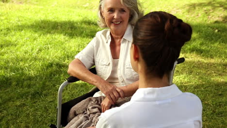 Krankenschwester-Spricht-Mit-Frau-Im-Rollstuhl-Draußen