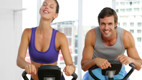 Fittes-Paar-Trainiert-Auf-Fahrrädern-Im-Fitnessstudio