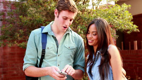 Two-students-standing-and-looking-at-smartphone