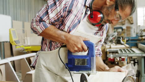 Side-view-of-carpenter-sawing-a-wood-plank