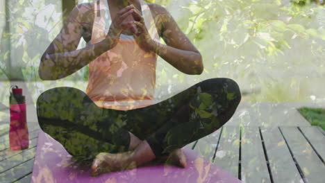 Animation-of-trees-over-african-american-woman-doing-yoga,-meditating,-slow-motion