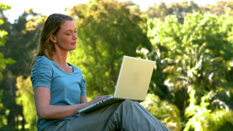 Mujer-Joven-Usando-Una-Computadora-Portátil-En-El-Parque