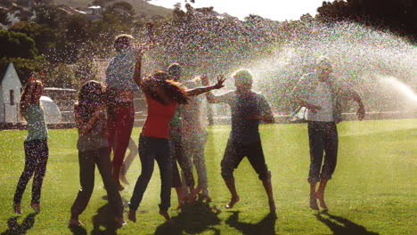 Schüler-Spielen-Mit-Sprinklern-Auf-Dem-Rasen-Herum