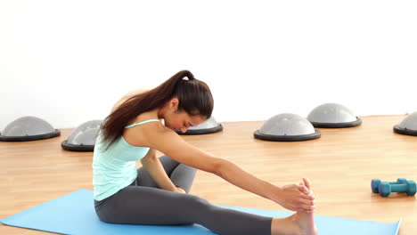Fit-brunette-stretching-on-exercise-mat