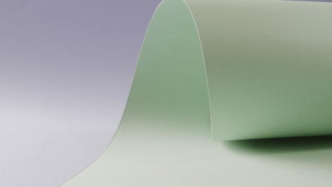Nahaufnahme-Eines-Hellgrünen,-Aufgerollten-Stück-Papier-Auf-Blauem-Hintergrund-Mit-Kopierraum-In-Zeitlupe