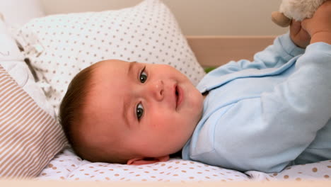 Baby-playing-with-teddy-in-his-crib