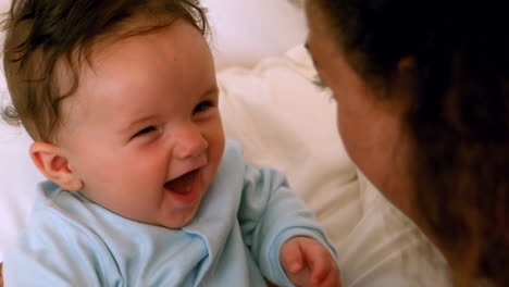 Mother-cuddling-her-baby-boy-on-bed