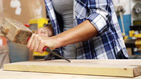 Focus-on-carpenter-using-hammer-and-chisel-on-a-wooden-plank