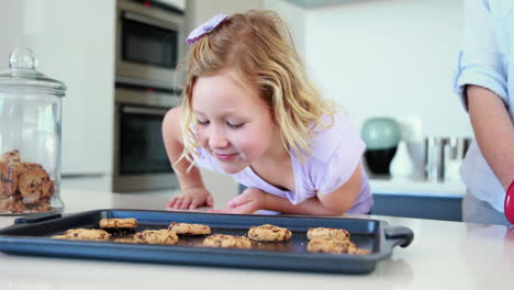 Madre-Sacando-Galletas-Calientes-Del-Horno-Con-Una-Niña-Oliéndolas