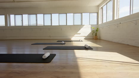 Sunlight-fills-spacious-yoga-studio,-mats-and-bolsters-ready-for-class